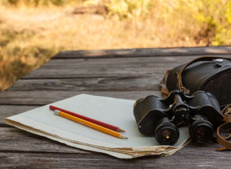 Binoculars notebook with a blank page on a wooden backgroundの写真素材