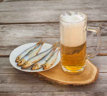 Glass of beer next to   plate  meats smoked fish  on a wooden tableの写真素材