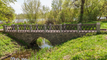 The old stone bridge in the arboretum Alexandria against the backdrop of the river Ros springのeditorial素材