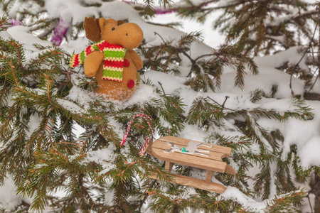 Funny toy moose with sledges on snow-covered branches of fir. Mass productionの写真素材