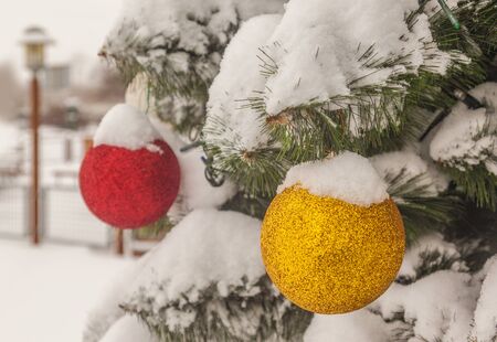 Snow-covered artificial Christmas tree with balls on the streetの写真素材