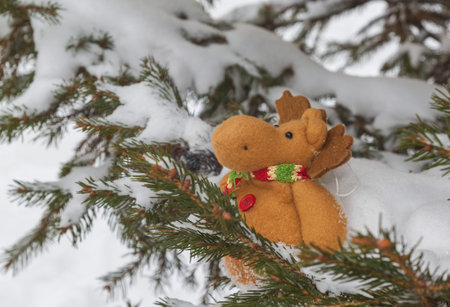 Funny toy moose on snow-covered branches of fir. Mass productionの写真素材
