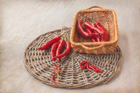 Harvest of red hot pepper in a basket on a gray table.の写真素材