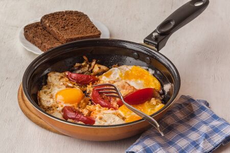 Fried eggs with onions and tomatoes in a pan. Bachelor's Dinnerの写真素材