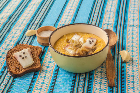 Corn porridge - banosh with toasted bacon, onions, rye bread with pepper and bacon, garlic and a spoon.の写真素材