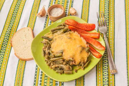 Fried green beans with onions and cheese and chunks of sweet pepper on a plate. Vegetarian lunch.の写真素材