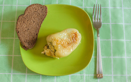 Fried stuffed bell peppers on a plate with black bread. Flat lay