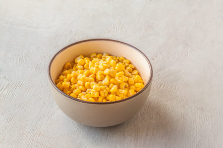 Canned sweet corn in a gray bowl on kuchen table.