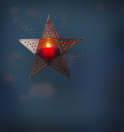 Vintage iron star-lantern with a candle on a dark background on the eve of the holidays. (mass produced product)の写真素材