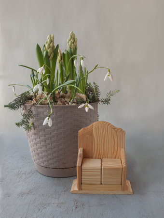 Flower pot-basket with blooming muscari, hyacinths, snowdrop next to Two-cube calendar with empty edges on gray background. Hello spring. Place for text. Background for cover, calendar, bannerの写真素材