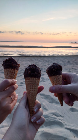 Ice cream in a waffle cone on the beach at sunset.