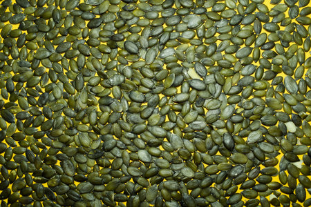 Pile of Raw Shelled Pumpkin Seeds on Yellow Backgroundの写真素材