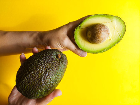 Hands Holding a Fresh Avocado Cut in Half