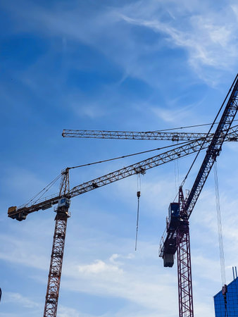 Tower Cranes Silhouette Against Blue Sky