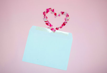 Blank card with heart shape made of rose petals on pink backgroundの写真素材
