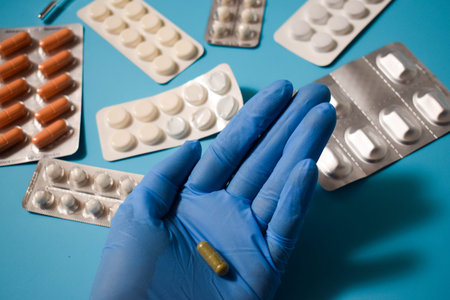 Tablets and capsules in the doctor's hand on a blue background