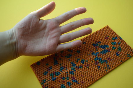 Hand of a girl with embroidery on a yellow background.