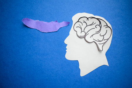 Paper human head with a brain and purple torn paper on blue background