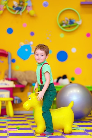 happy kid riding a toy in kindergartenの写真素材
