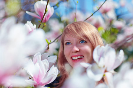 happy woman in spring magnolia flowersの写真素材