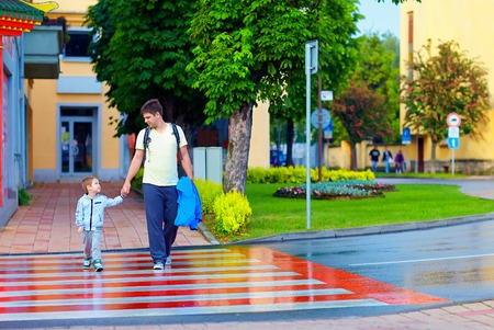 father and son crossing the city street on crosswalkの写真素材