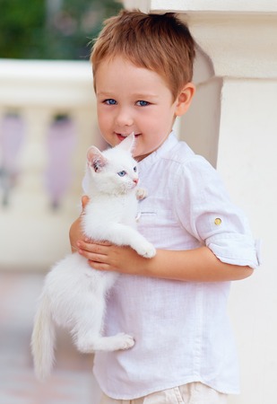 cute kid holding white kittenの写真素材