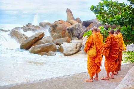 group of buddhist monks watching storm on rocky beachの写真素材