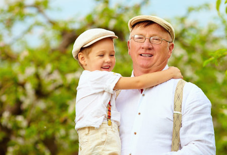 Cute grandpa with grandson on hands in spring gardenの写真素材