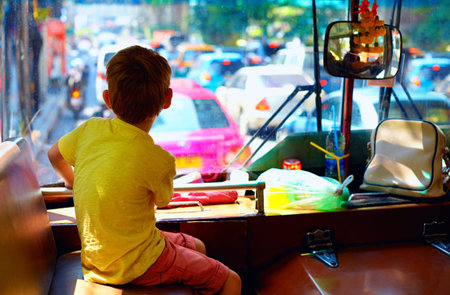 young boy sitting in local public bus while traveling through the city of Bangkokの写真素材