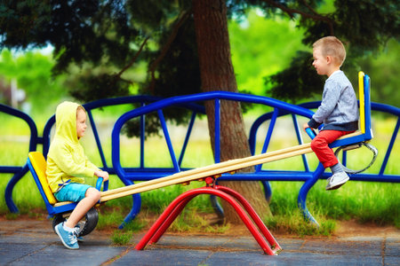 cute kids having fun on seesaw at playground