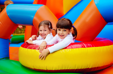 happy kids girls having fun on inflatable attraction playground