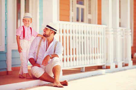 fashionable father and son sitting and talking on caribbean streetの写真素材