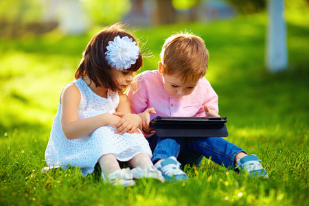 two cute kids using digital tablet in summer gardenの写真素材