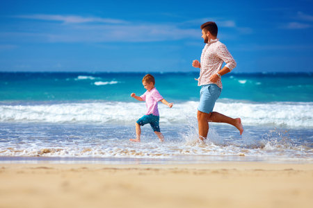 happy excited father and son running on summer beach, enjoy lifeの写真素材