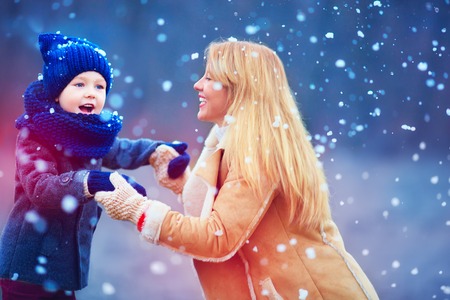 happy mother and son having fun under winter snowの写真素材