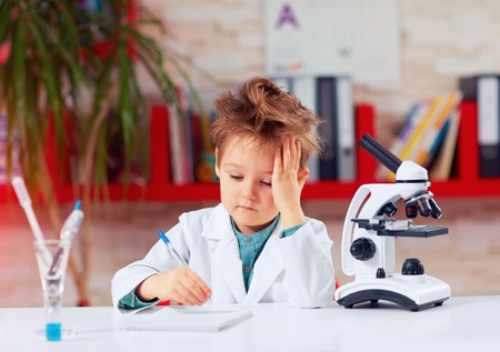 tired little scientist writing notes after experiments in school labの写真素材