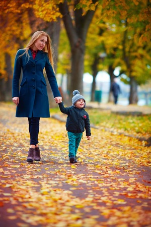 young mother with little son walking on autumn streetの写真素材