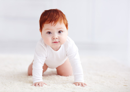 happy, nine months old baby crawling on carpet at home