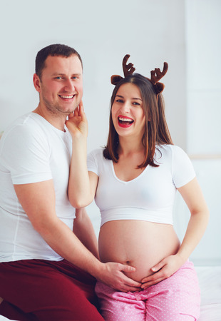 funny pregnant couple in pajamas having fun at homeの写真素材