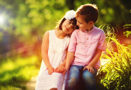cute kids in love, sitting together in spring gardenの写真素材