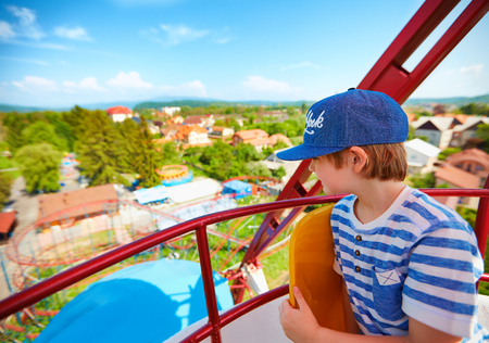 excited boy enjoying the view from ferris wheel in amusement parkの写真素材