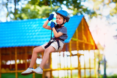 young boy passing the cable route high among the trees, extreme sport in adventure parkの写真素材