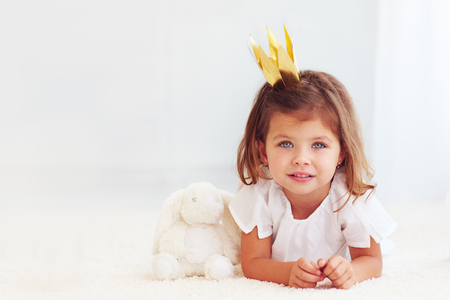 portrait of cute little baby girl laying on carpet with toy bunnyの写真素材