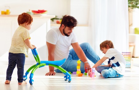 infant toddler baby walking with go cart while father and kid playing games togetherの写真素材