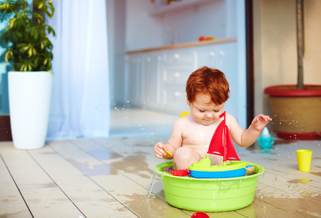cute redhead toddler baby having fun with water on summer terraceの写真素材
