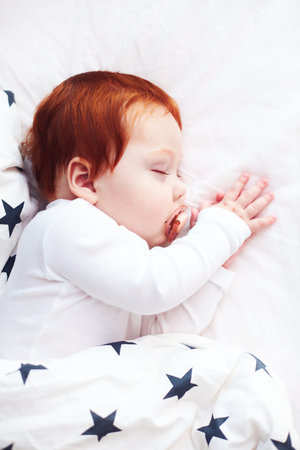 top view of redhead infant baby sleeping peacefully in bedの写真素材