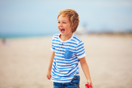 young delighted boy, kid playing with a toy propeller, having fun on summer beachの写真素材