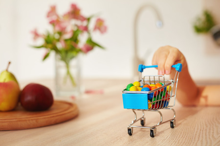 mini shopping trolley full of candies on kitchen deskの写真素材