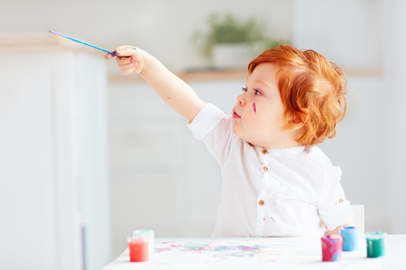 happy little baby artist drawing with colorful paints at homeの写真素材