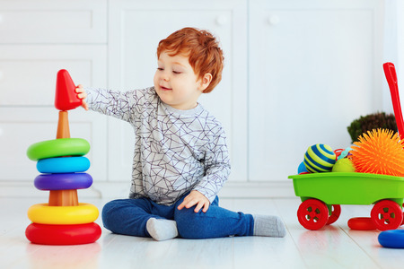 happy toddler baby boy sorting colorful rings on pyramidの写真素材